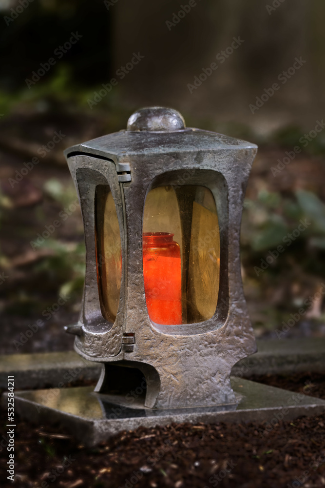 Fototapeta premium funeral lantern in a cemetery at dusk with a burning candle