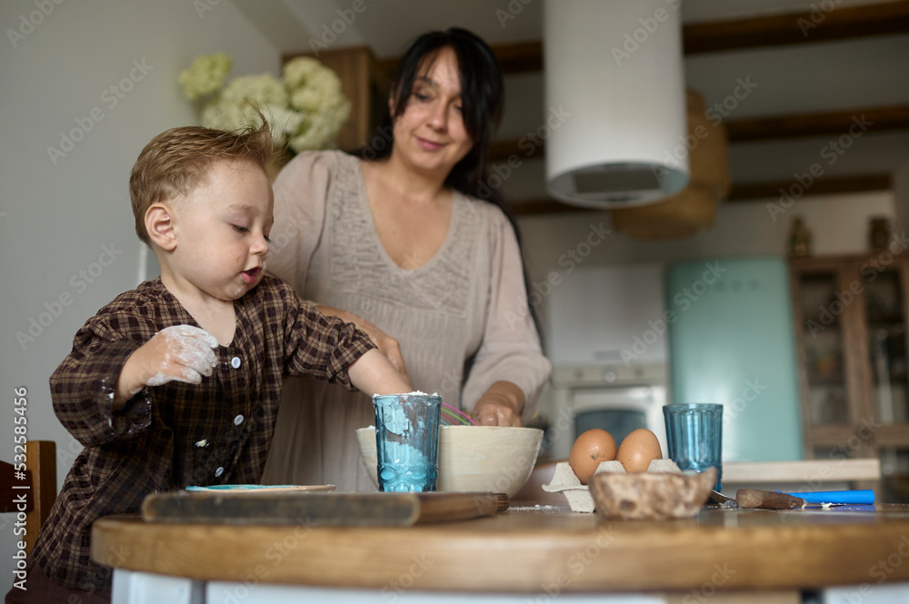 mother baking food in kitchen with her son mother baking food in kitchen with her son