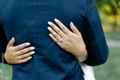 Closeup of Bride's Hands on Groom's Suit photo