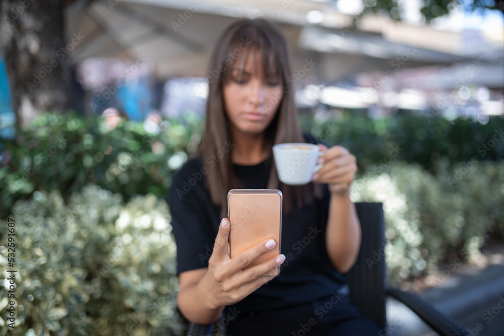 Morning in cafe - attractive woman in black drinkin coffe and make selfie photo for social networks Morning in cafe - attractive woman in black drinkin coffe and make selfie photo for social networks