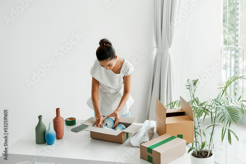 woman putting handmade jug or vase into the box