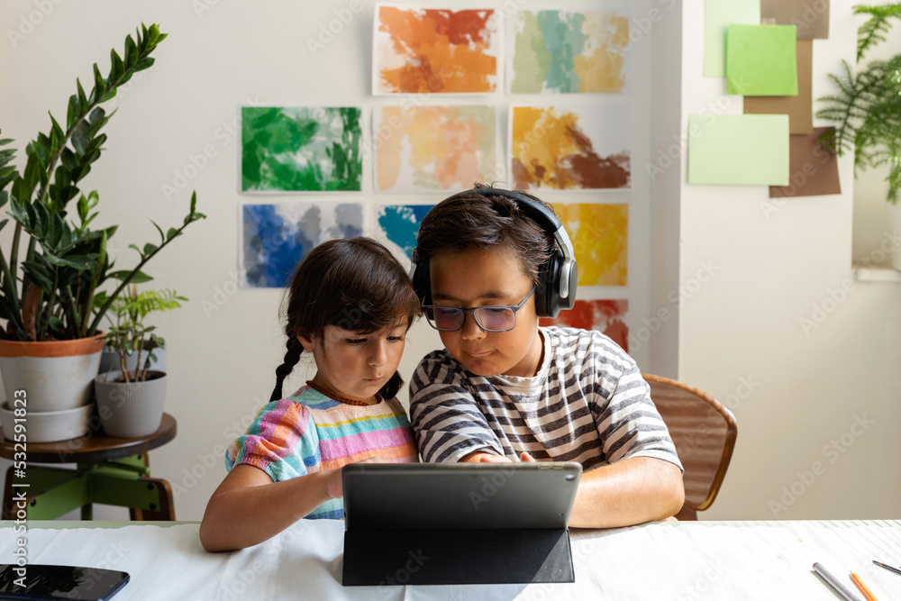 Kids sharing tablet in painting studio Kids sharing tablet in painting studio