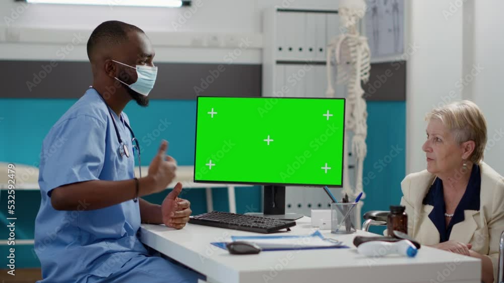 Male nurse and woman with impairment analyzing greenscreen display on computer. Using isolated chromakey template and mockup copyspace during pandemic, checkup with wheelchair user. Male nurse and woman with impairment analyzing greenscreen display on computer. Using isolated chromakey template and mockup copyspace during pandemic, checkup with wheelchair user.
