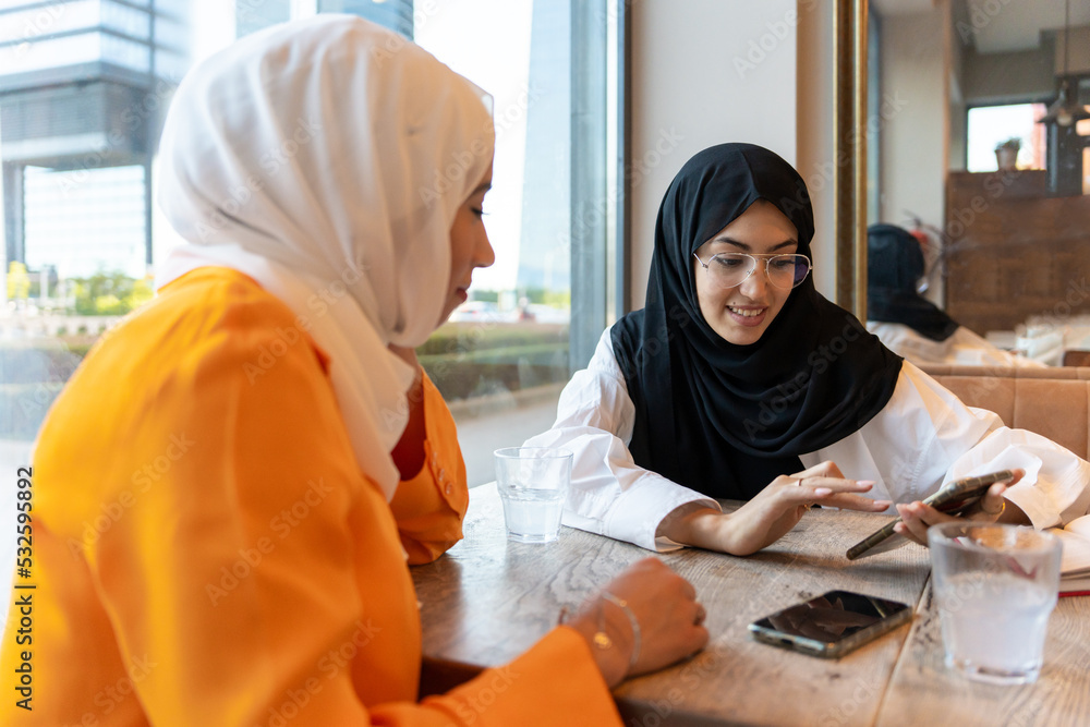 Two Muslim Girls Talking In A Urban Cafe. Two Muslim Girls Talking In A Urban Cafe.