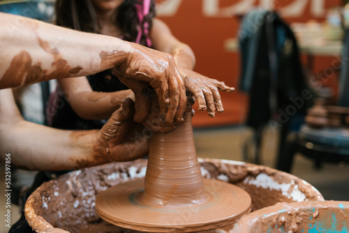 Unrecognizable people creating clay vessel