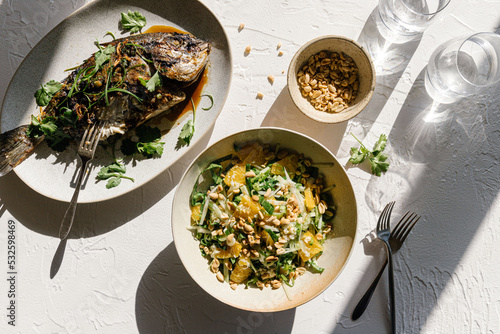 Spread of salad, grilled fish and glassware photo