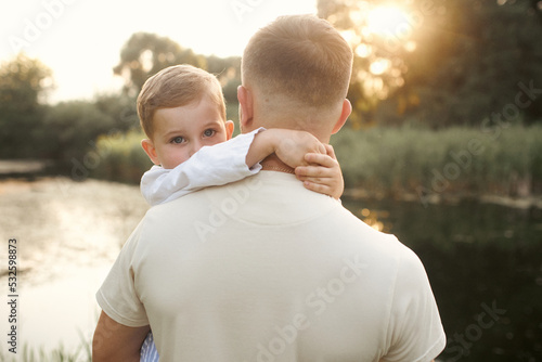 dad holds his son in his arms in nature photo