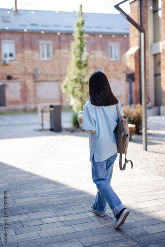 Female passerby strolling with beverage  photo