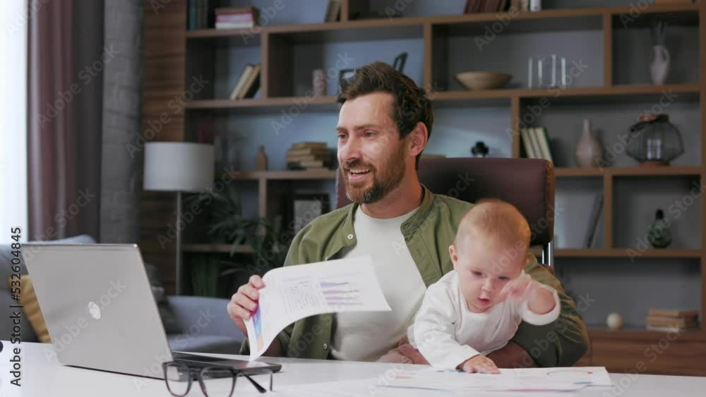 Father on maternity leave, holding an online conference, a meeting in the home office with a small child in his arms. Dad with a child. Freelancer combines child care and work. Paternity leave Father on maternity leave, holding an online conference, a meeting in the home office with a small child in his arms. Dad with a child. Freelancer combines child care and work. Paternity leave