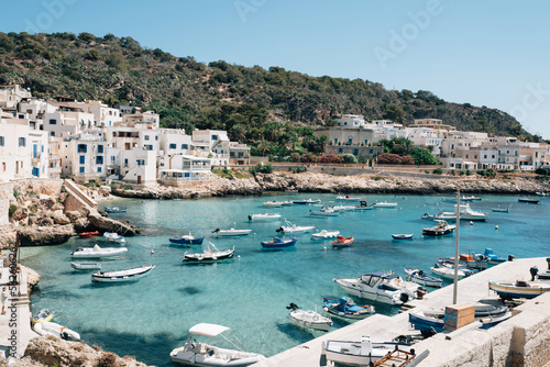 Boats floating in clear blue waters of Levanzo harbour under blue sky photo