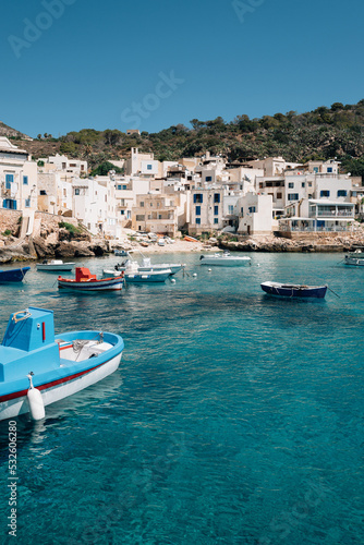 Boats of different colours float in the blue waters of Levanzo harbour photo