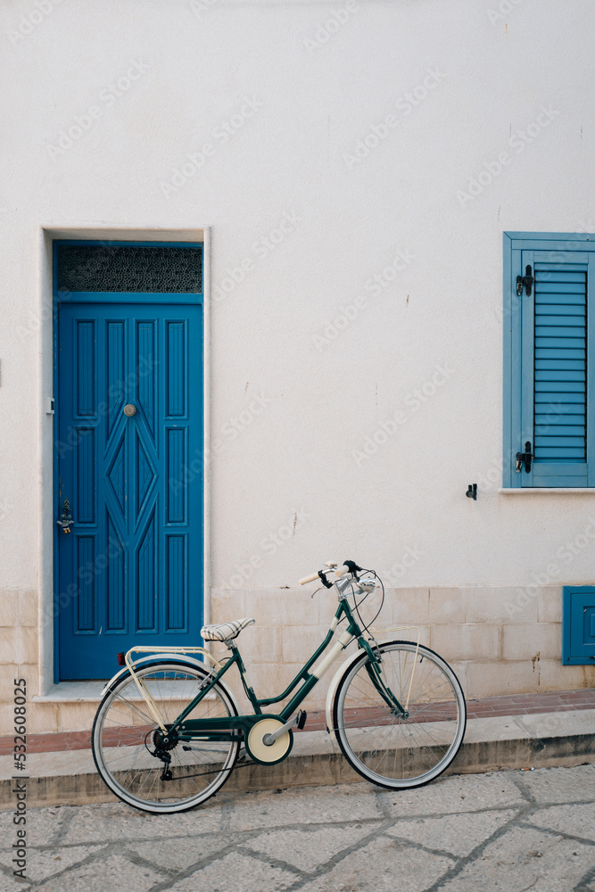 Bicycle in front of characteristic blue door and window in Marettimo Bicycle in front of characteristic blue door and window in Marettimo
