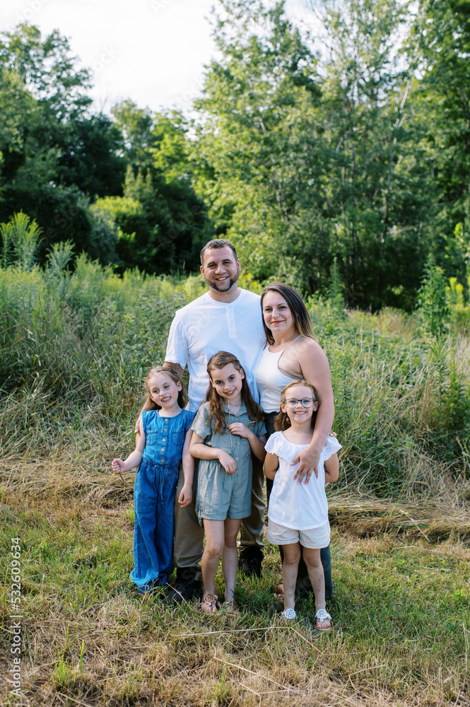 Family of five standing in a field together on a summer day Family of five standing in a field together on a summer day