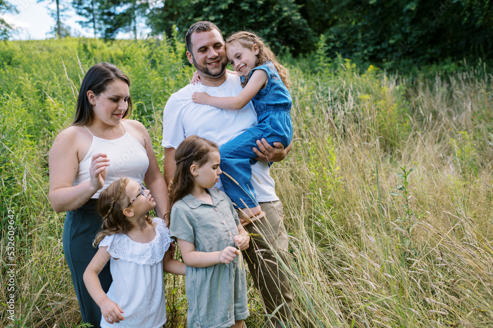 Family of five standing in a field together on a summer day Family of five standing in a field together on a summer day