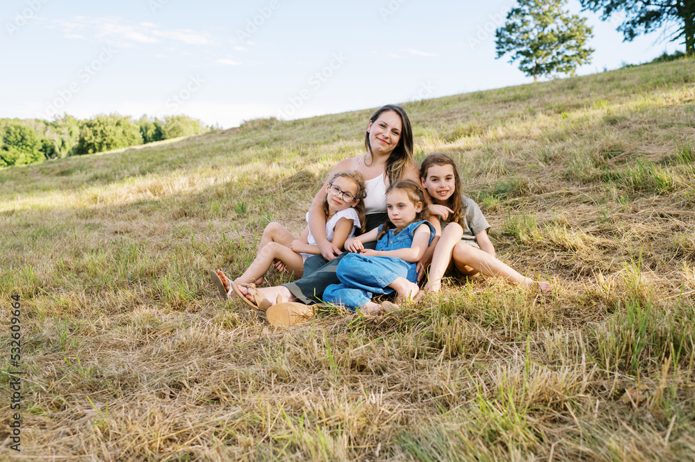 Portrait of a mother and her three daughters sitting down in a field Portrait of a mother and her three daughters sitting down in a field