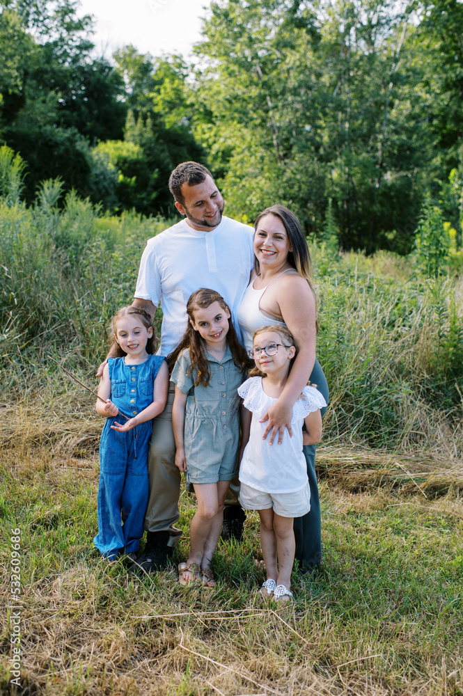 Family of five standing in a field together on a summer day Family of five standing in a field together on a summer day