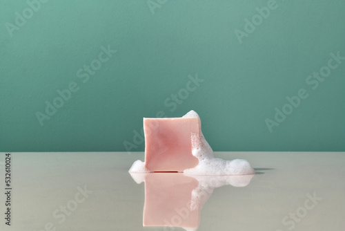 Piece of pink soap and foam on a reflective surface photo