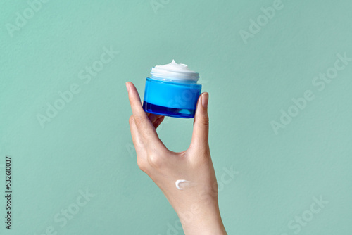 Woman's hand holds a round jar of body cream photo