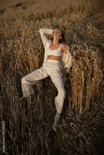 Girl in minimalist garment resting on wheat  photo