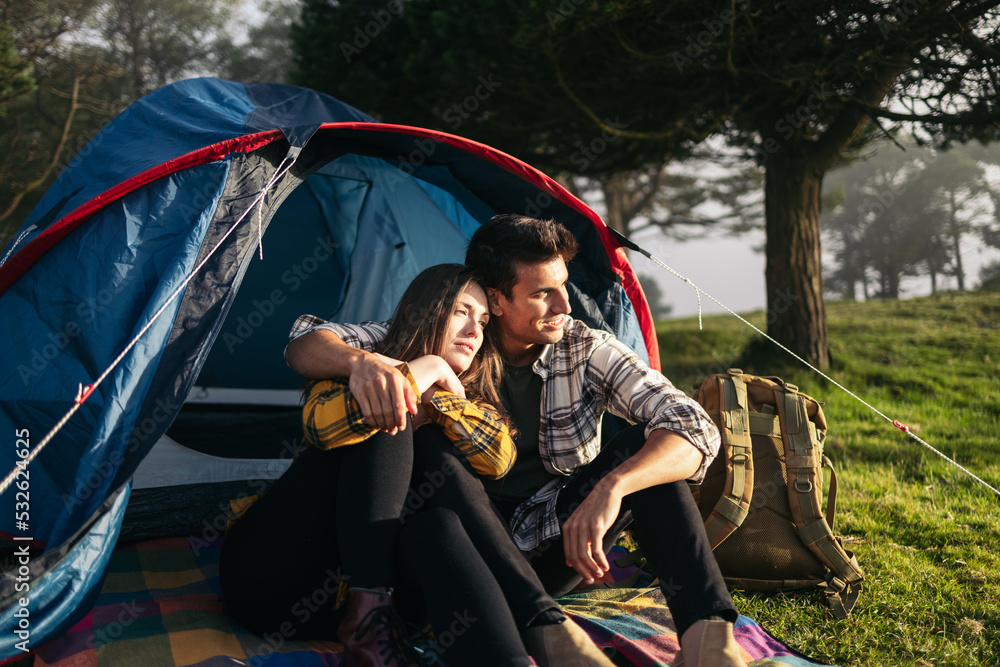 Embraced couple watching the sunset camping in the forest Embraced couple watching the sunset camping in the forest