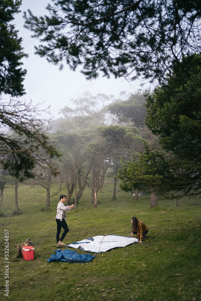 Couple setting up a tent in the forest for camping Couple setting up a tent in the forest for camping