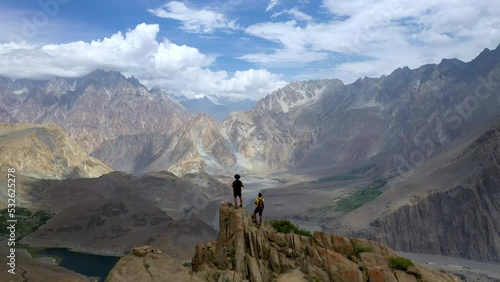 Drone shot of passing over two hikers on peak at Passu Cones  Pakistan, cinematic wide aerial shot photo