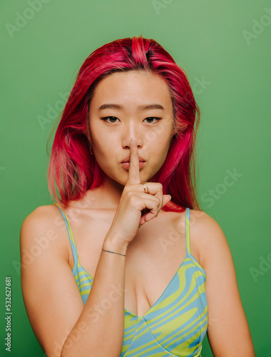 Young woman touching lips asking for silence photo