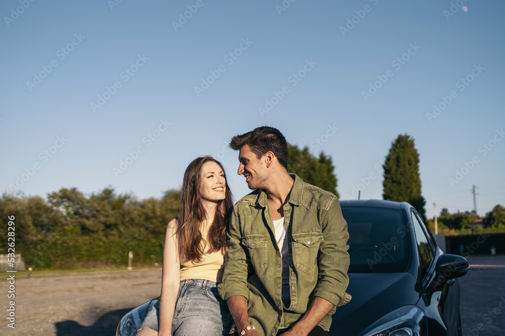 Couple leaning on car at sunset Couple leaning on car at sunset