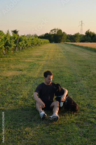 Man hugs his black dog in a dield photo