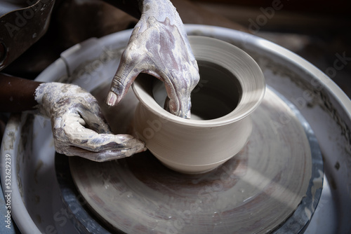 Closeup of woman working with clay on the pottery wheel photo