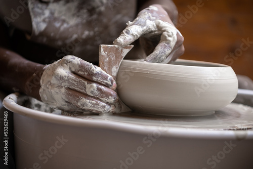 Closeup of woman shaping clay edges on pottery wheel photo