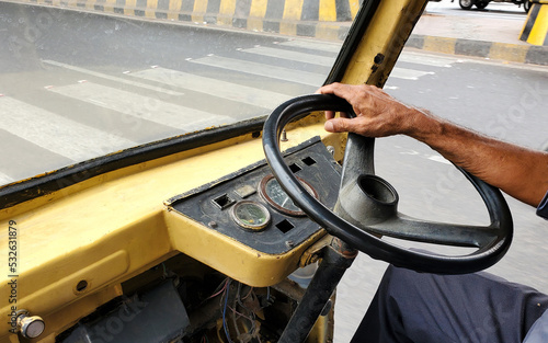 view of Indian Auto Rickshaw driver hand on driving wheel in the road photo