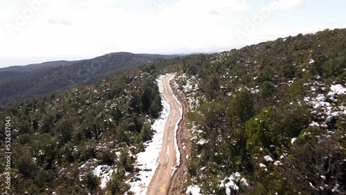 Fast push in aerial shot of dirt road in the middle of the snowy woods in Oncol Park, Chile. photo