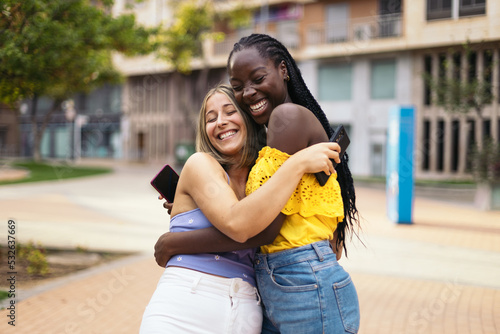Multiracial female friends hugging and happy at the street photo