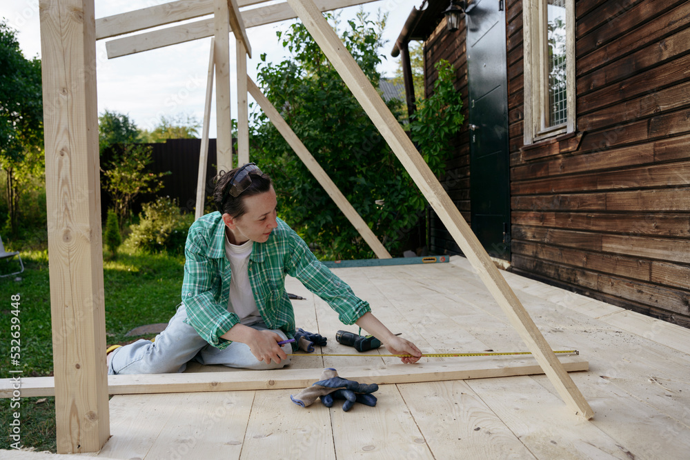 A female carpenter at work on a project in the backyard A female carpenter at work on a project in the backyard