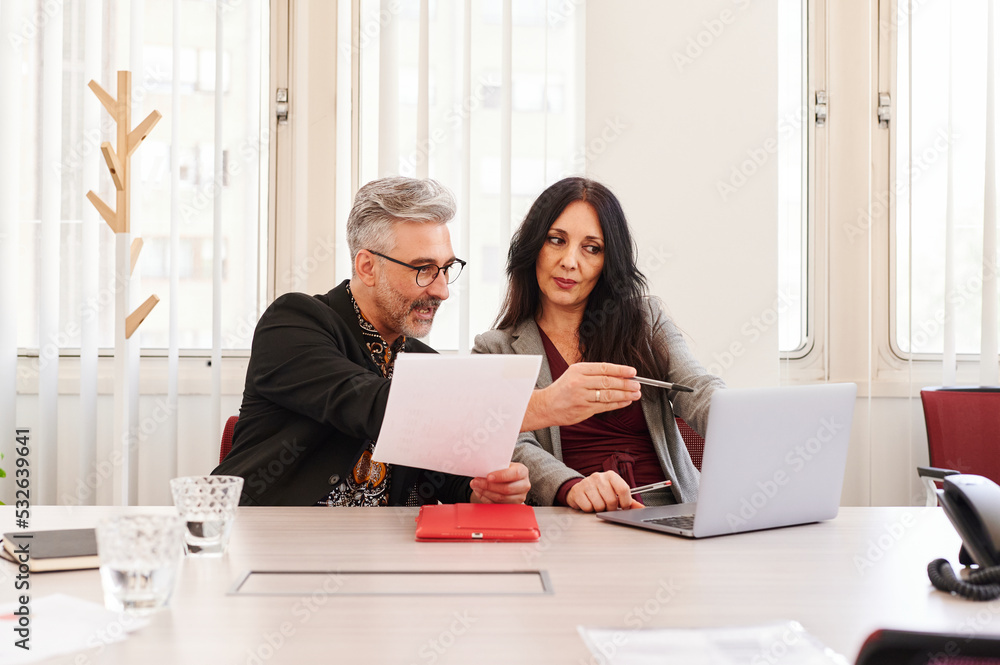 © Ivan Gener/Stocksy - Businesspeople discussing paperwork in an office © Ivan Gener/Stocksy - Businesspeople discussing paperwork in an office
