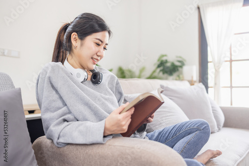 Beautiful Asian woman reading a book in her living room at home. Free Download Beautiful Asian woman reading a book in her living room at home. - GFXLoad