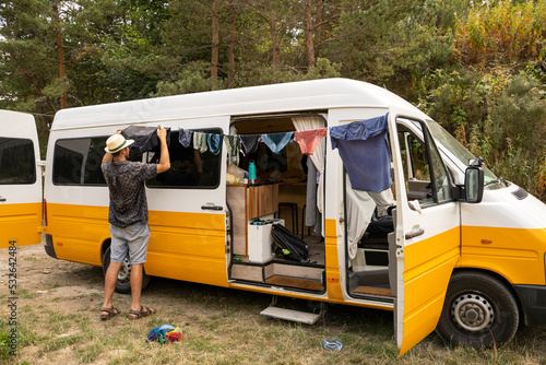 Man doing laundry by hand in camper van in nature photo