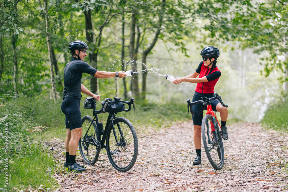 Happy cyclists watering each other during ride Happy cyclists watering each other during ride