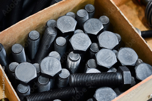 Pile of hardened blued metal bolts for fastening in crate