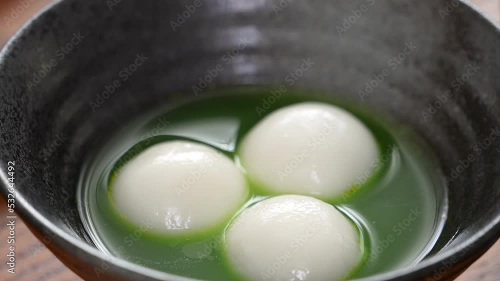 Matcha big tangyuan soup in a black bowl. Matcha big tangyuan soup in a black bowl.