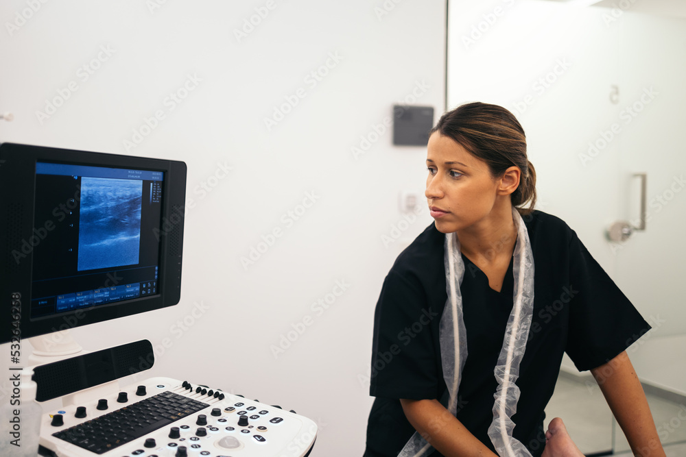 Physiotherapist doing an ultrasound scan to a patient in the clinic Physiotherapist doing an ultrasound scan to a patient in the clinic