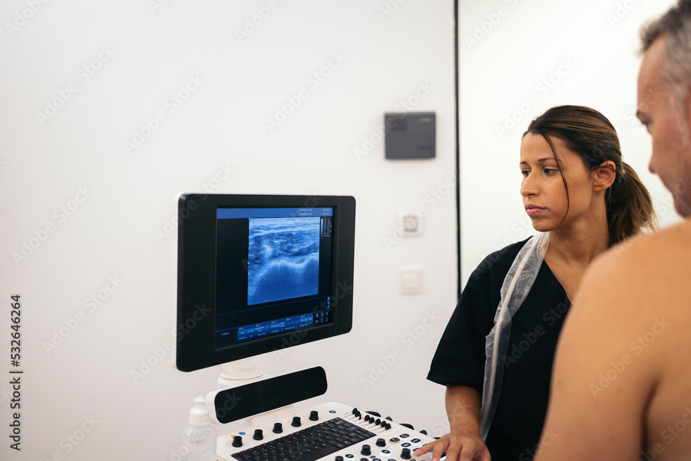 Physiotherapist doing an ultrasound scan to a patient in the clinic Physiotherapist doing an ultrasound scan to a patient in the clinic
