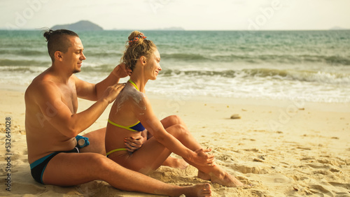 Hot sexy loving couple having sun block. Woman to put sunscreen man. Young girl and guy in hugging using sun cream. Concept rest tropical resort, traveling tourism happy summer holidays