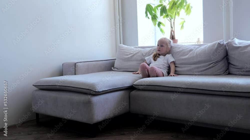 Little girl sitting on the couch looking ahead Little girl sitting on the couch looking ahead