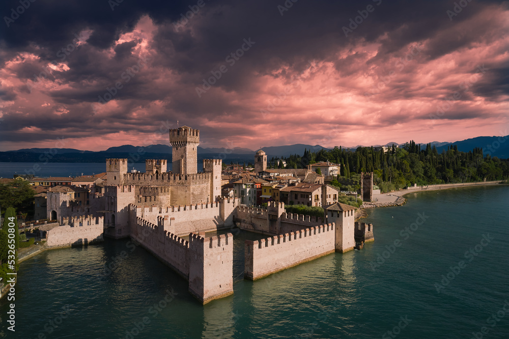Scaligero Castle at sunrise, Lake Garda, Italy. Pink clouds over Scaligero Castle aerial view.