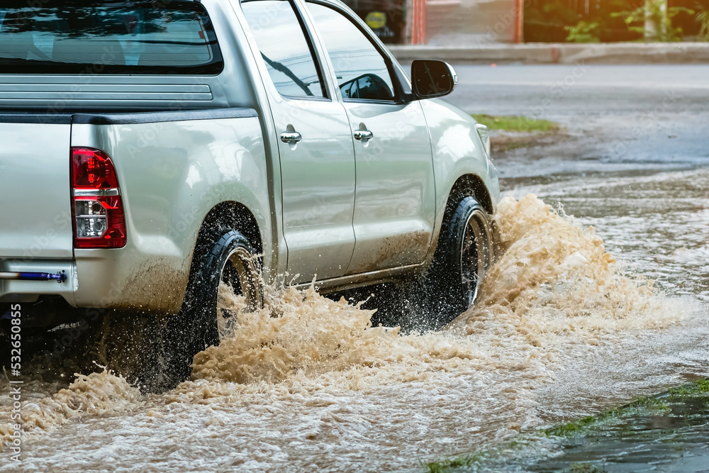 Pickup truck passing through flooded road. Driving car on flooded road