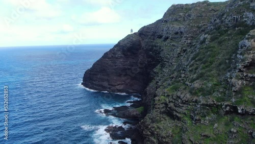 Magnificent coastal views from the steep volcanic sea cliffs of Makapu'u Lighthouse. Aerial parallax circling the lava rock walls revealing the ocean tidepools below. photo