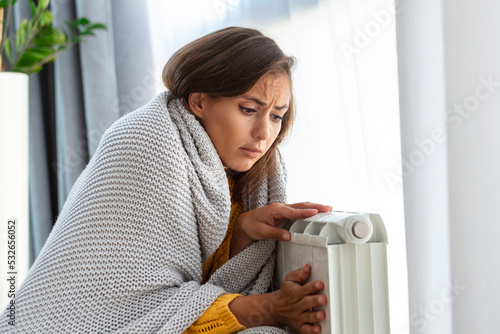 Fotografia Woman freezing at home, sitting by the cold radiator