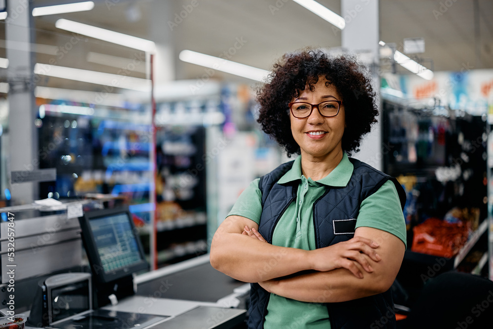 Happy supermarket cashier with her arms crossed looking at camera. Happy supermarket cashier with her arms crossed looking at camera.